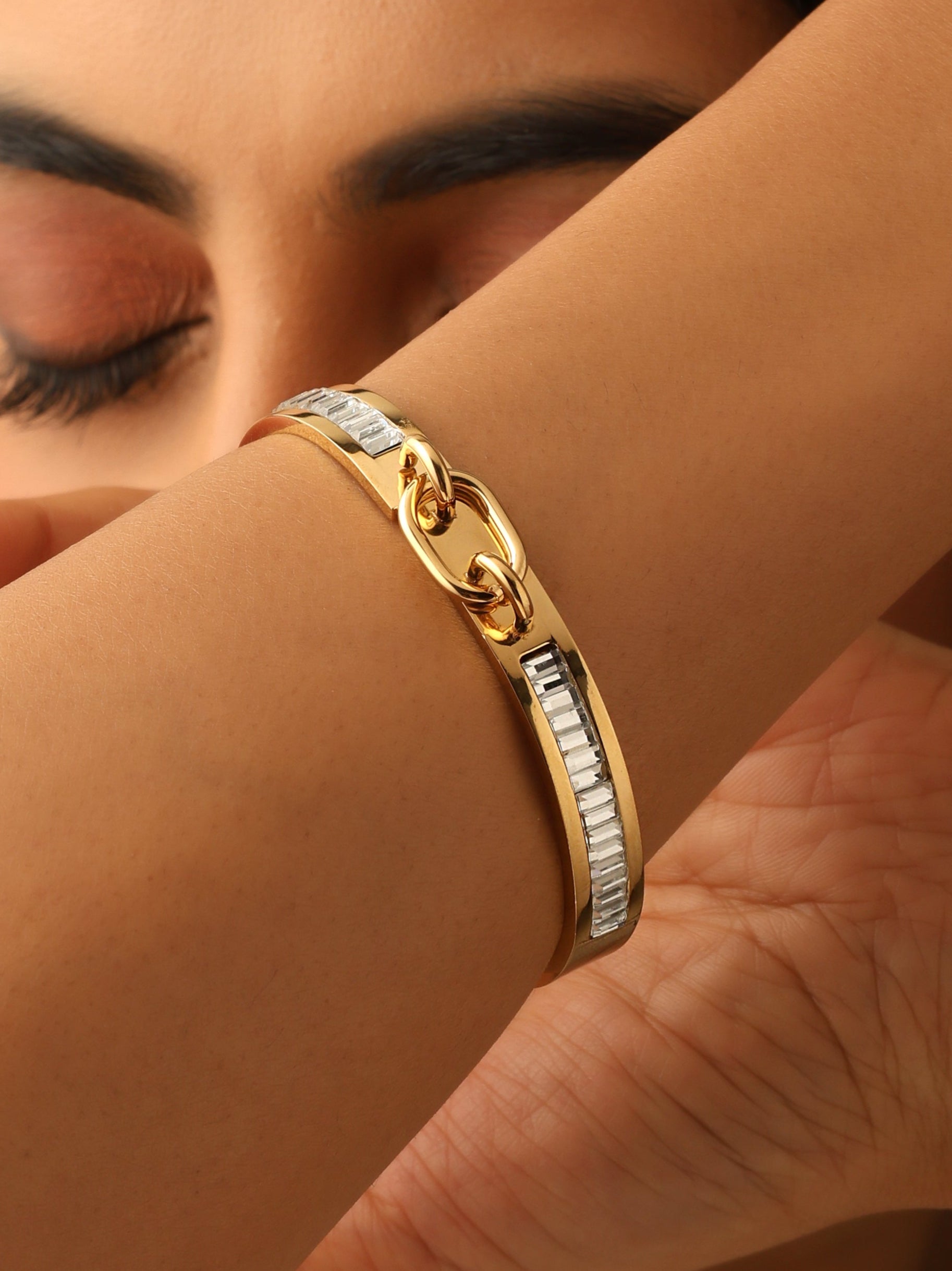 Close-up of a person's wrist wearing two gold bracelets.
