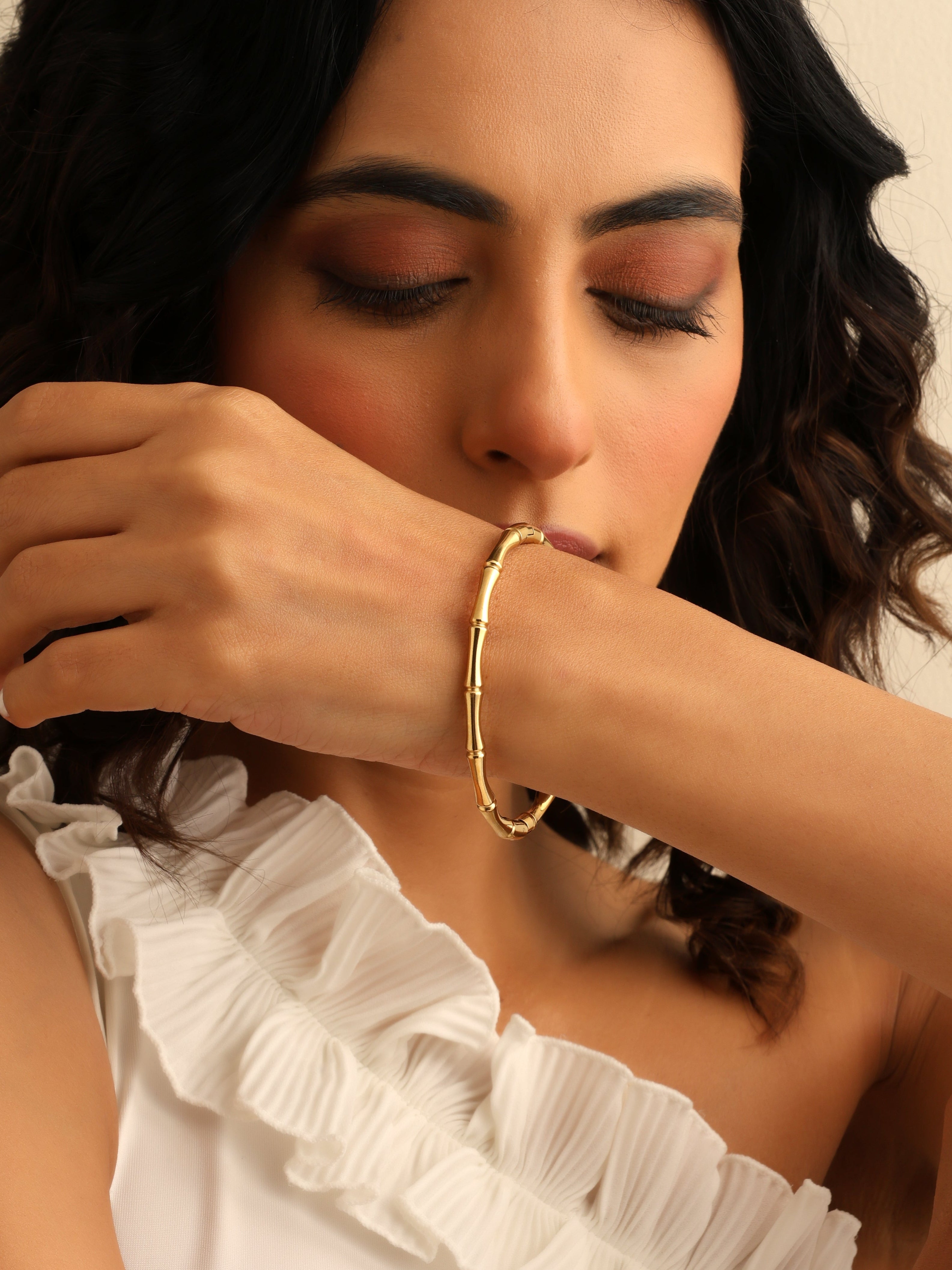 Woman wearing a gold bracelet with a neutral background