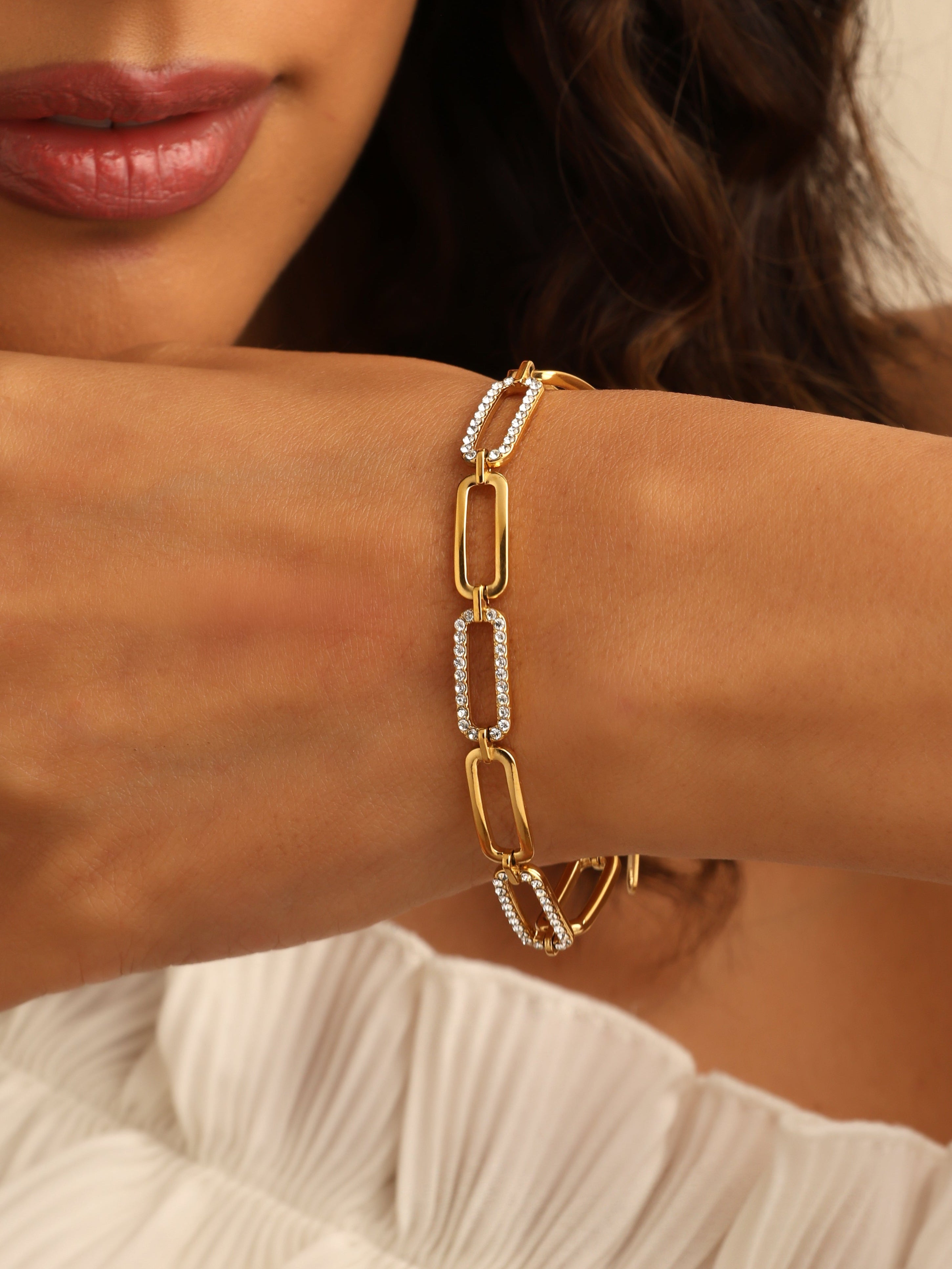 Close-up of a woman's wrist wearing a gold bracelet with diamond accents.