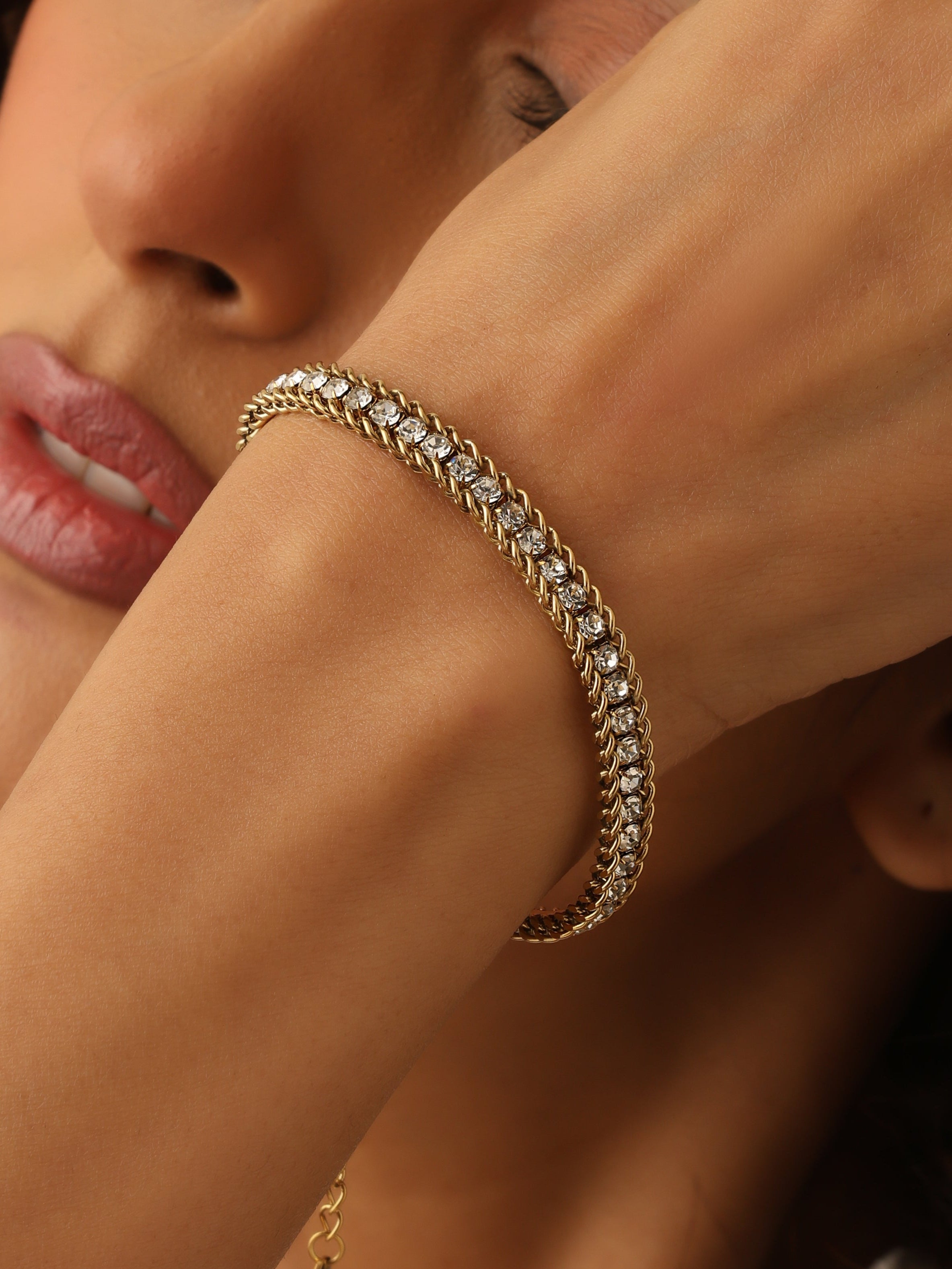 Close-up of a woman's arm wearing a gold bracelet with a blurred background