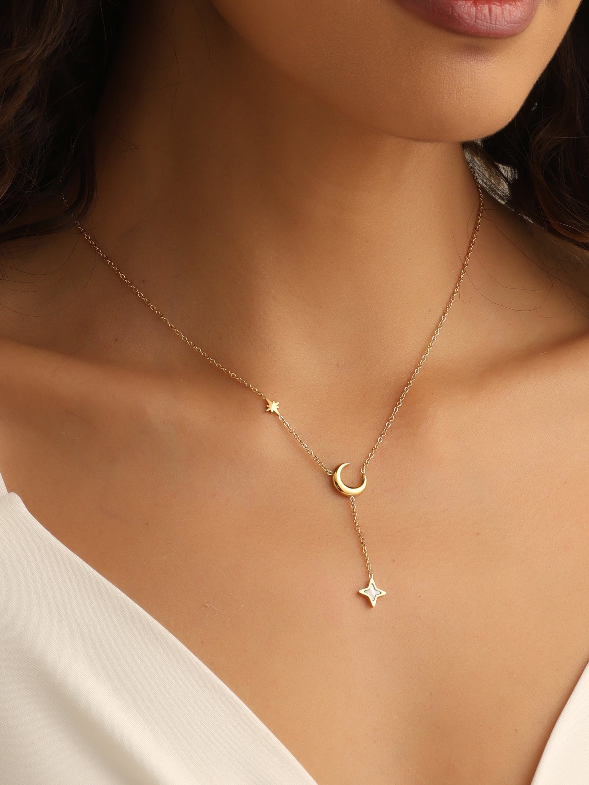 Necklace with star and moon pendants on a model wearing a white top.