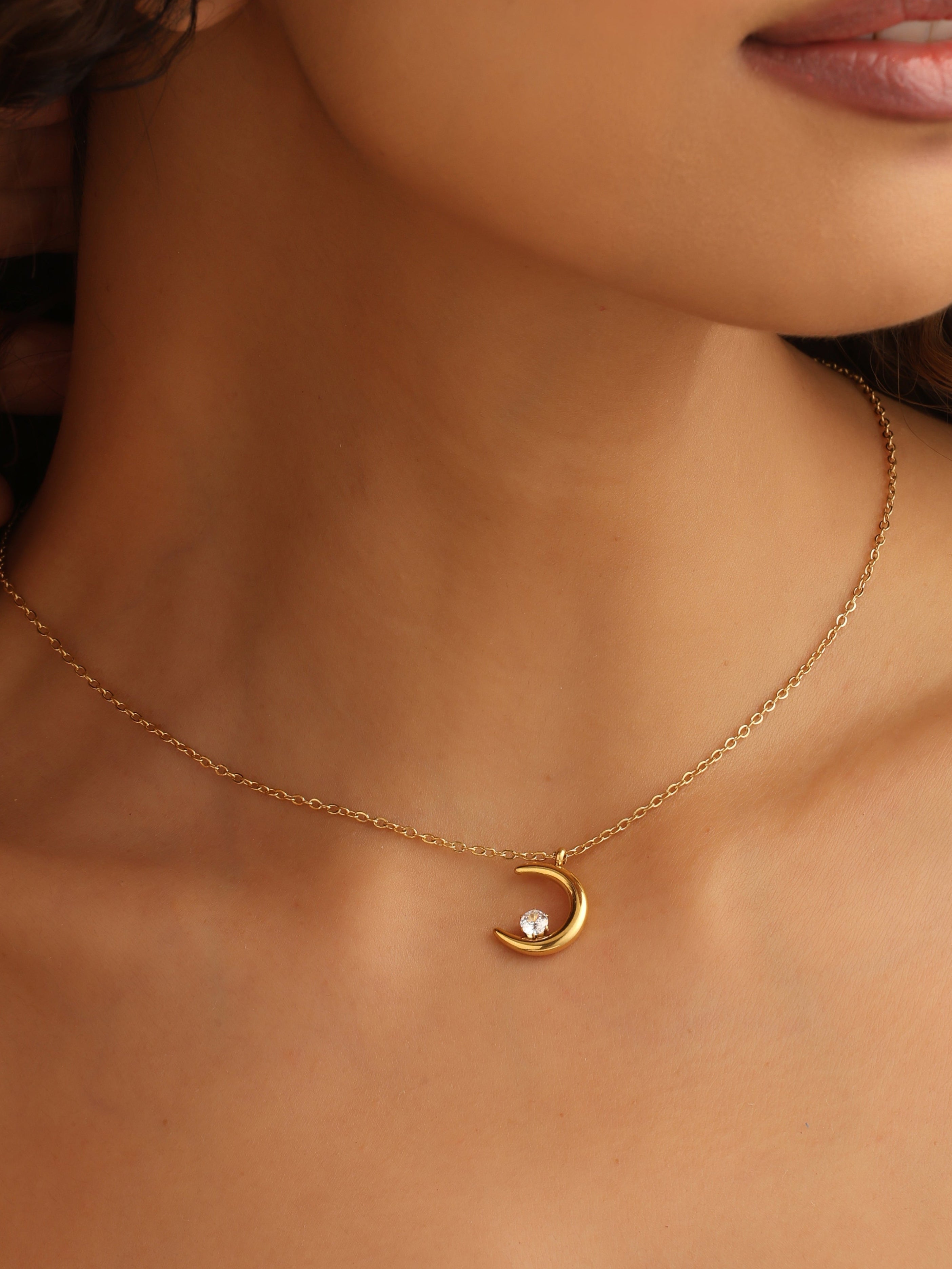 Gold necklace with a moon pendant on a person's neck