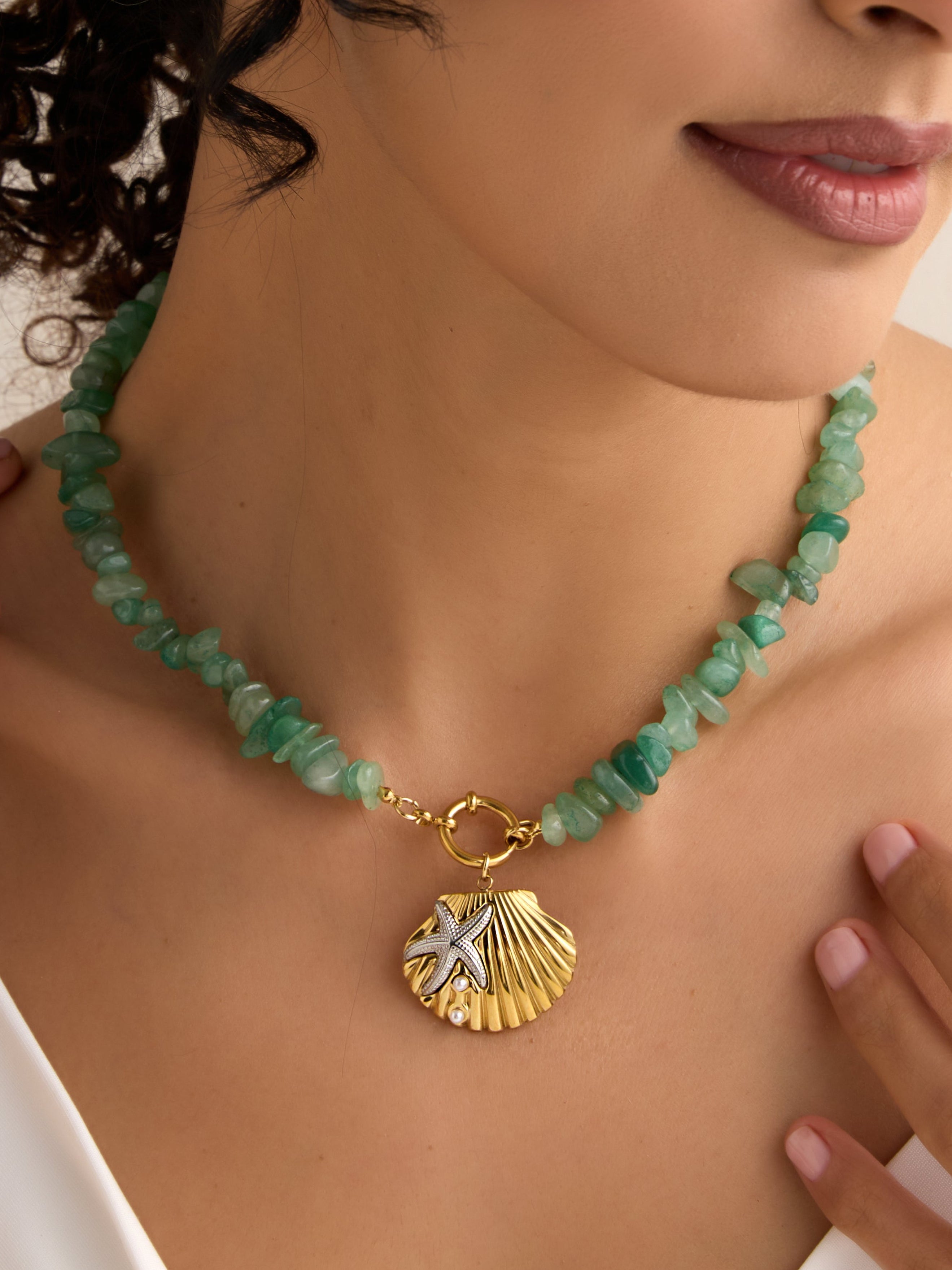 Klissaa Necklace with green beads and gold shell pendant worn by a person