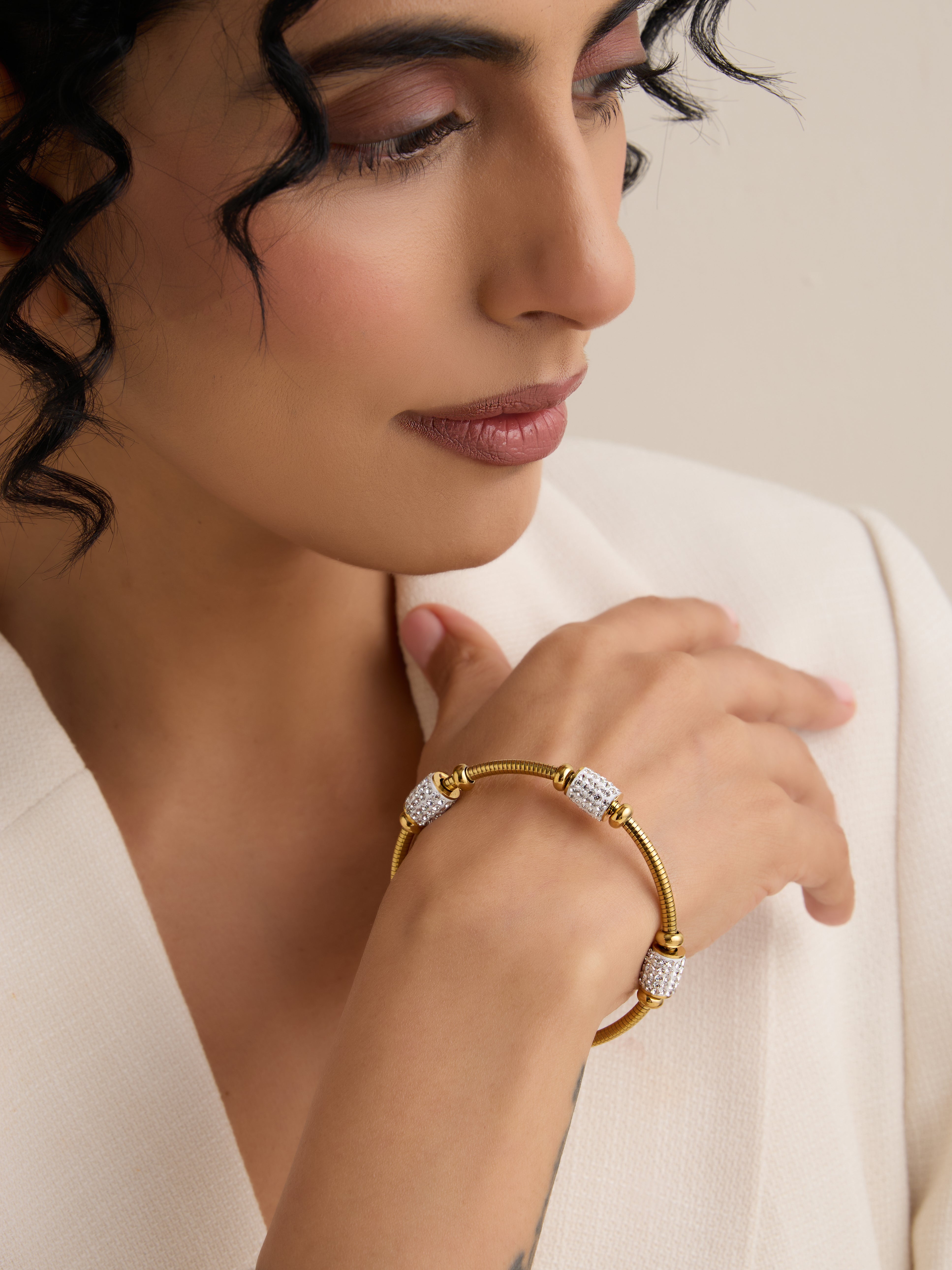 klissaa Gold bracelet with diamond accents on a beige background
