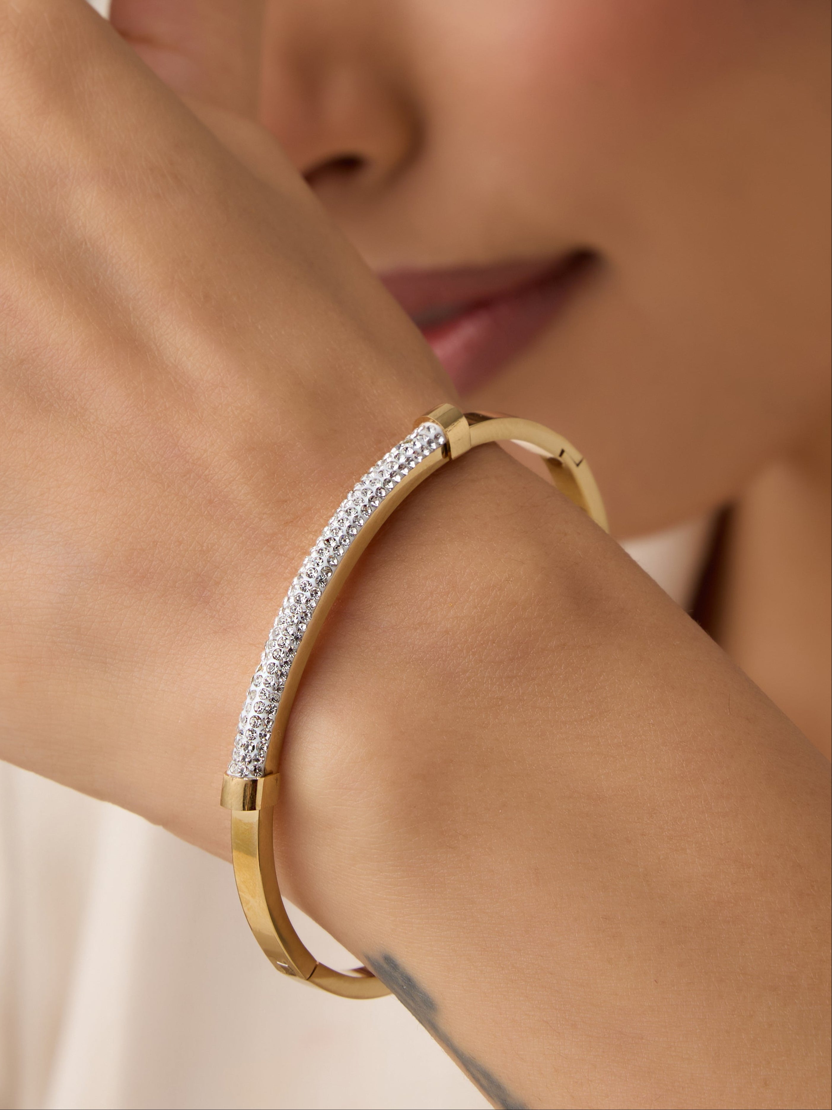 Woman wearing a gold bracelet with a blurred background