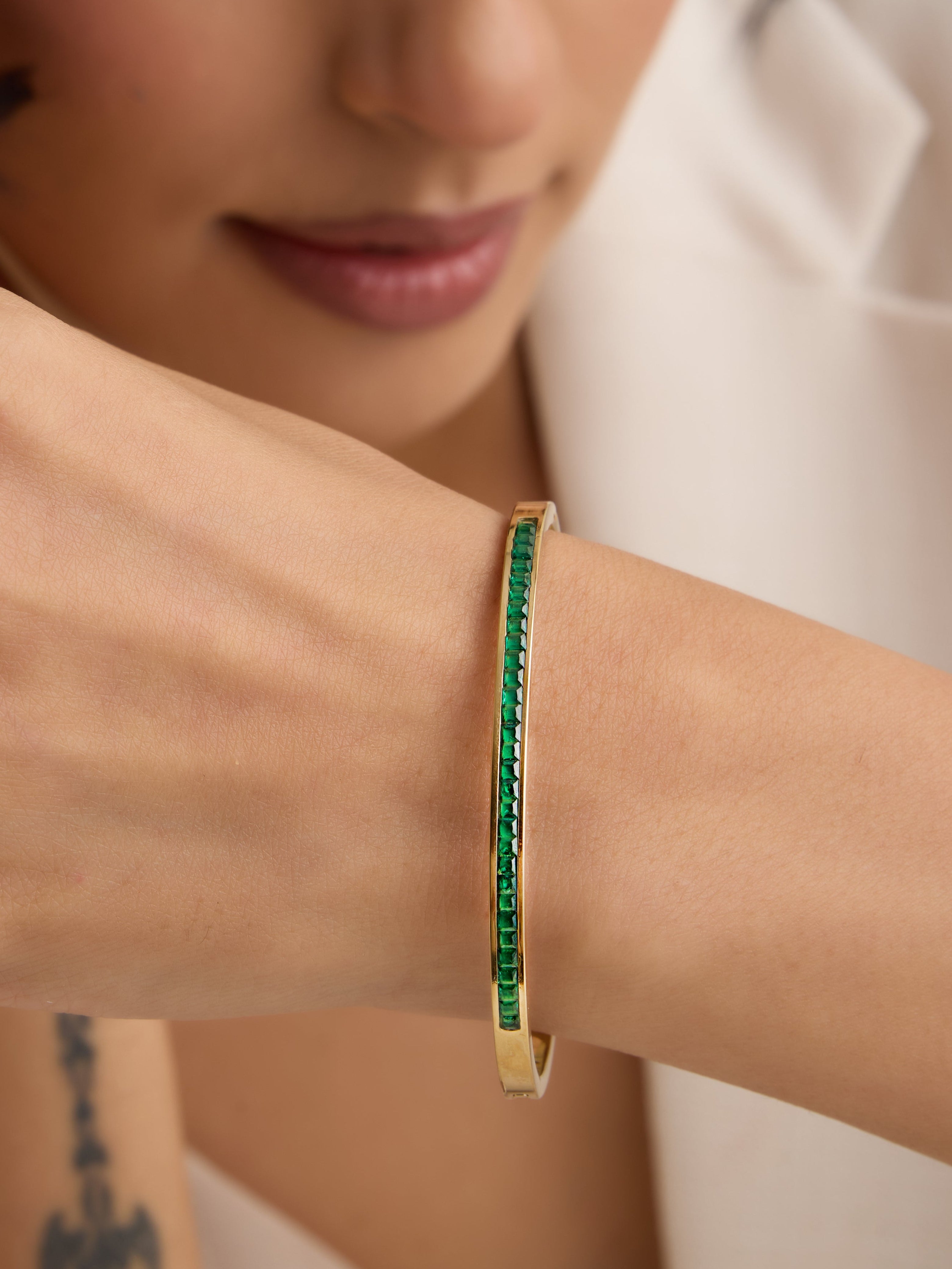 Woman wearing a green bracelet on her wrist with a neutral background