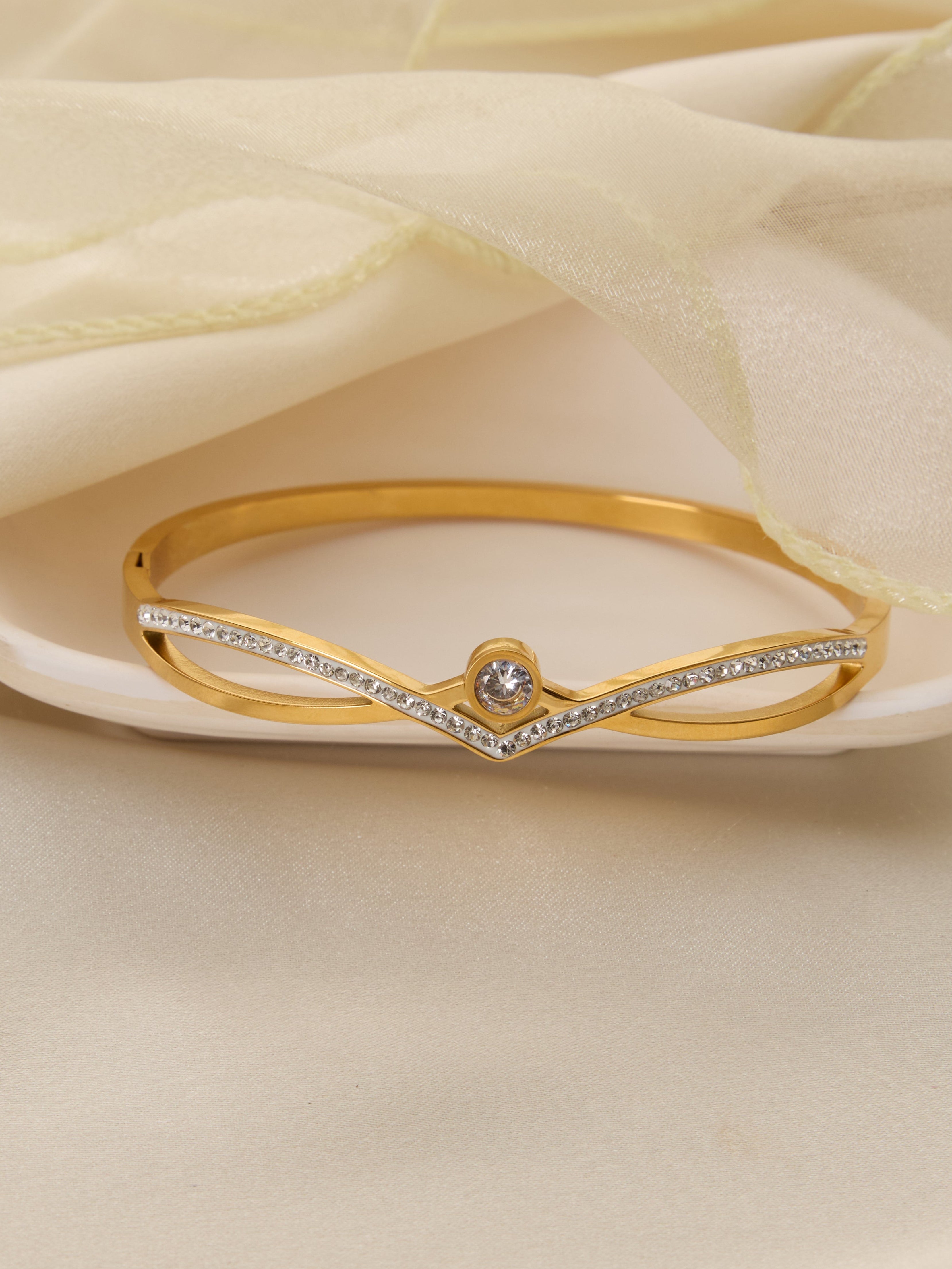 Gold bracelet with a diamond on a beige fabric background