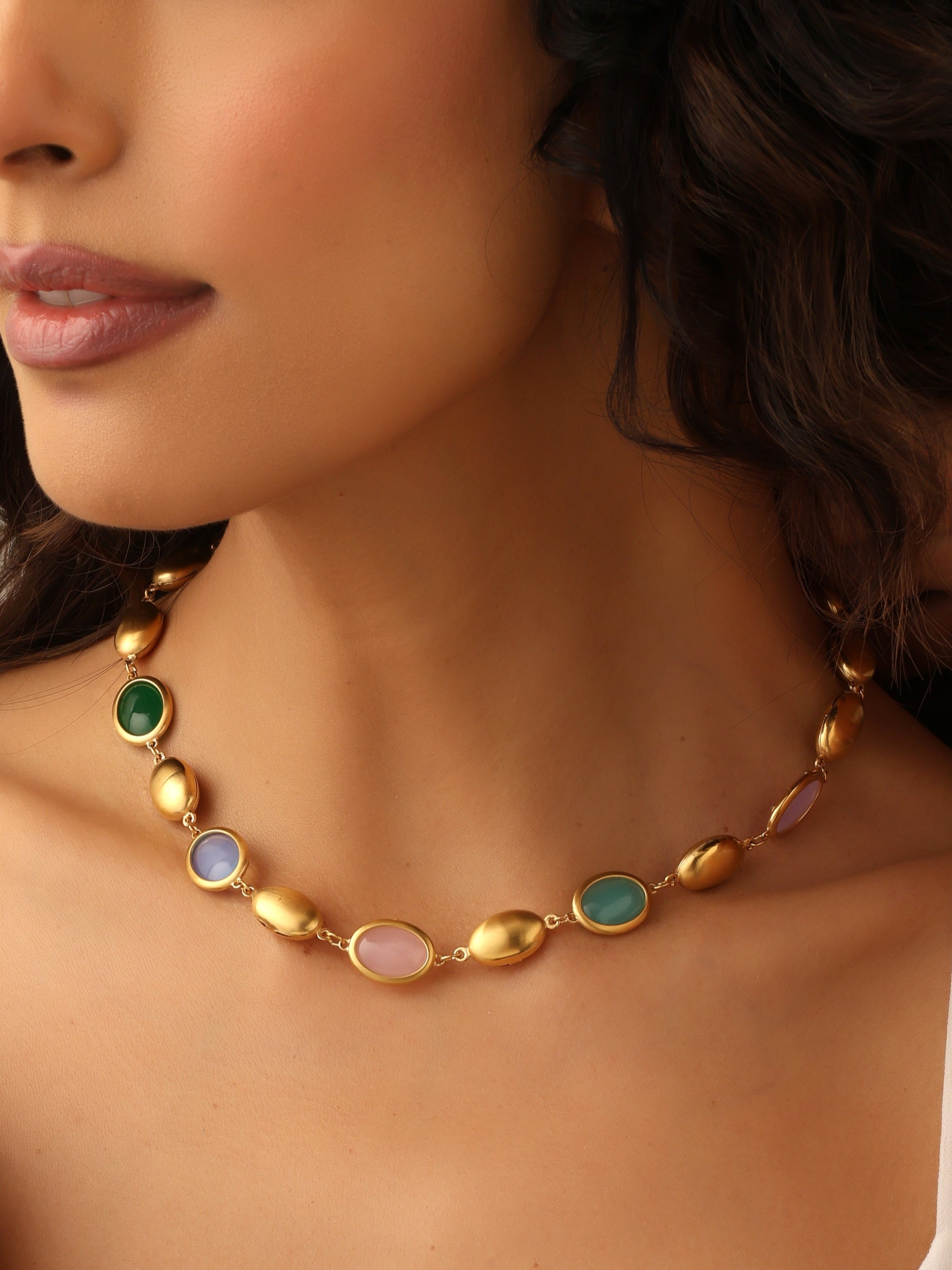Woman wearing a gold necklace with colored stones
