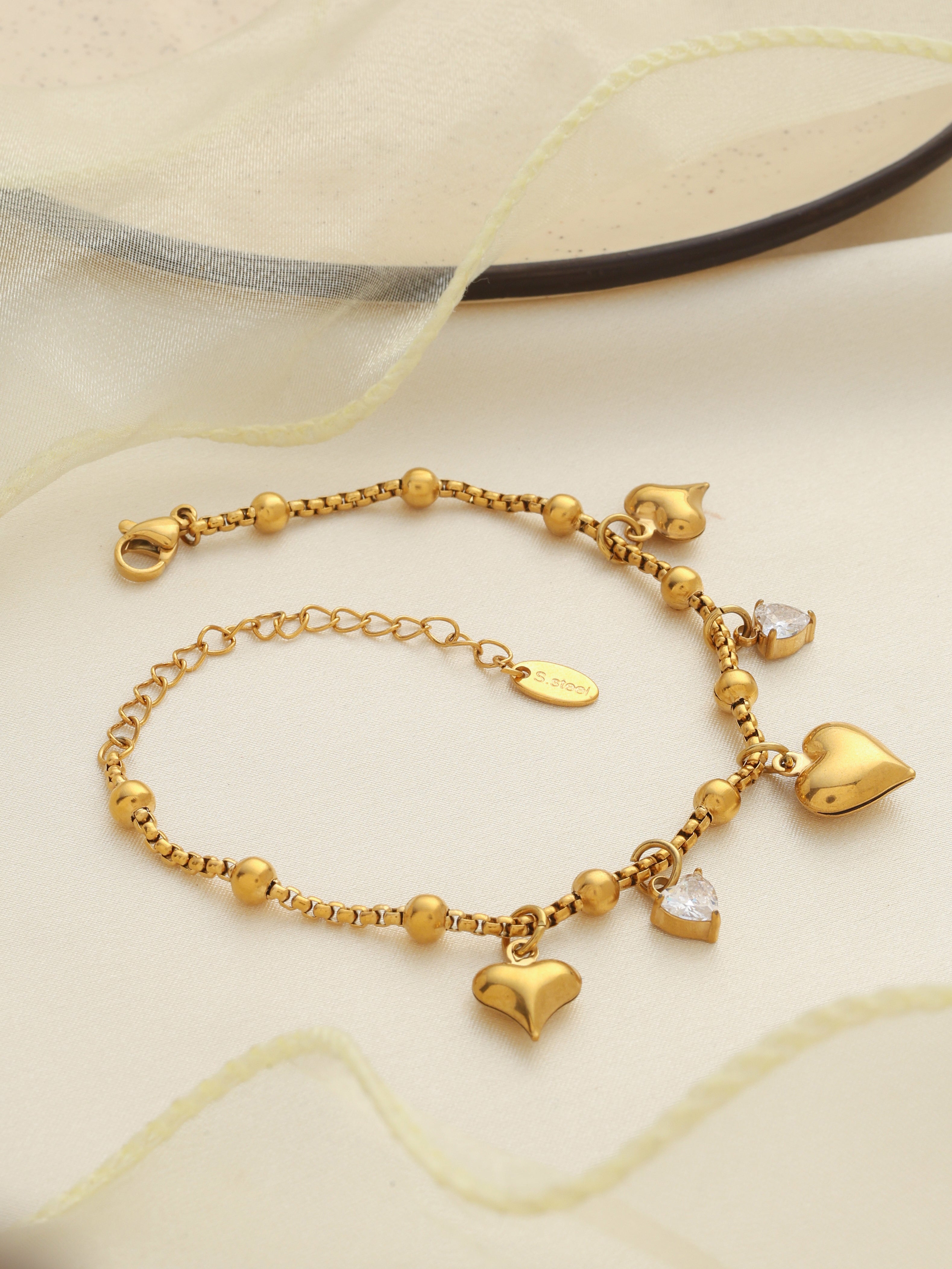 Gold bracelet with heart-shaped charms on a light background