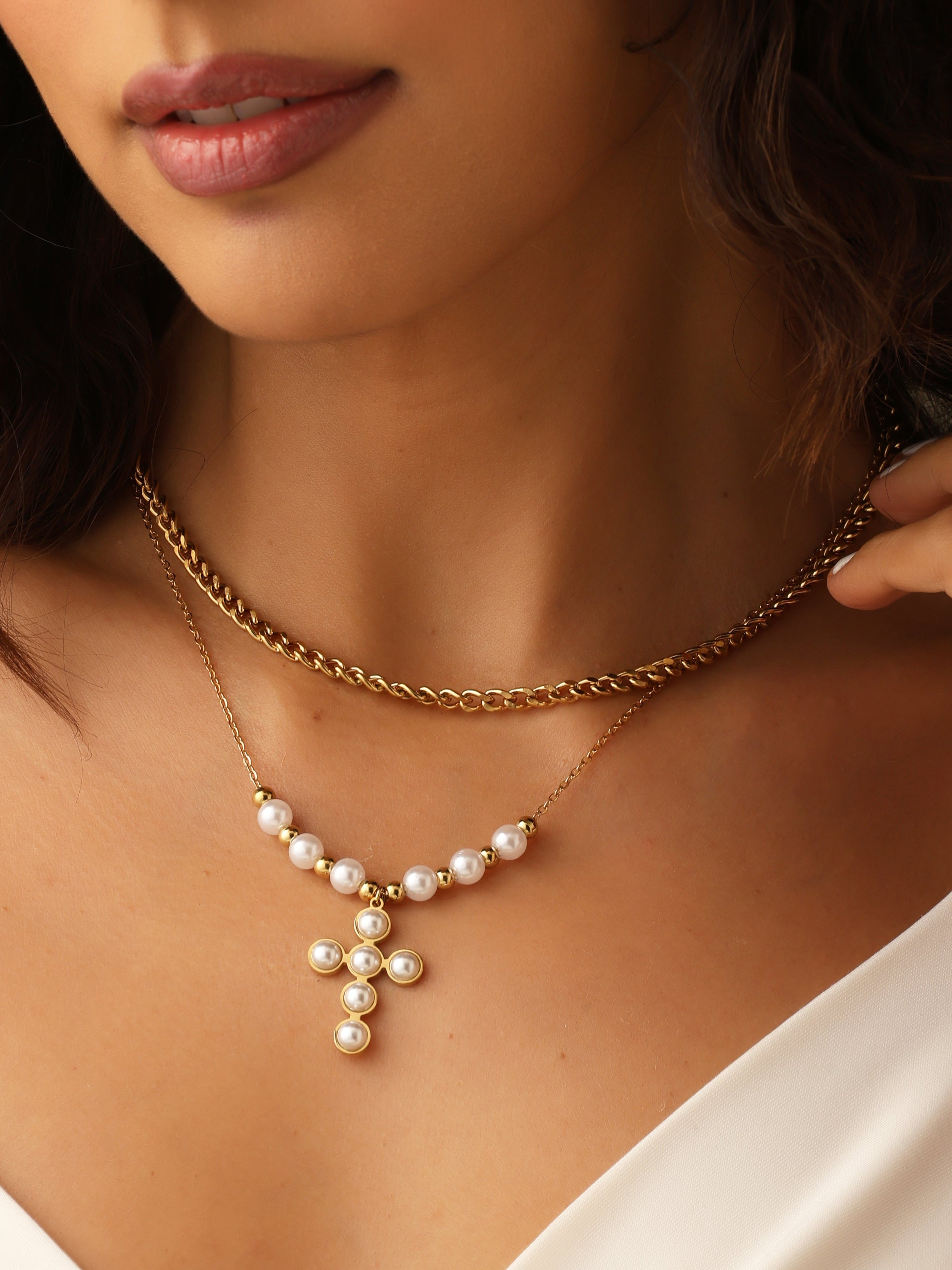 Close-up of a woman wearing a gold necklace with a pearl pendant.