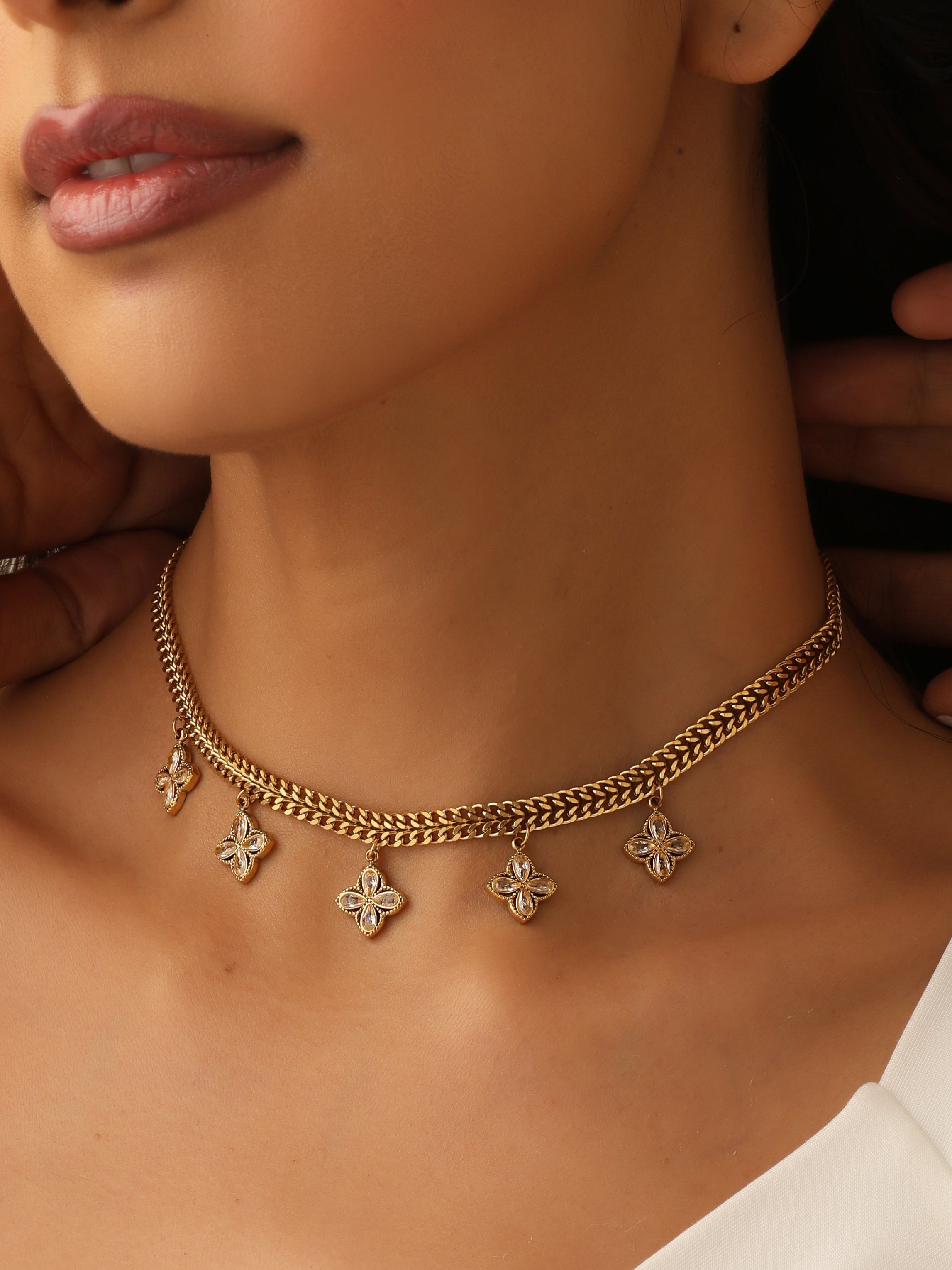 Close-up of a person wearing a gold necklace with star-shaped pendants.