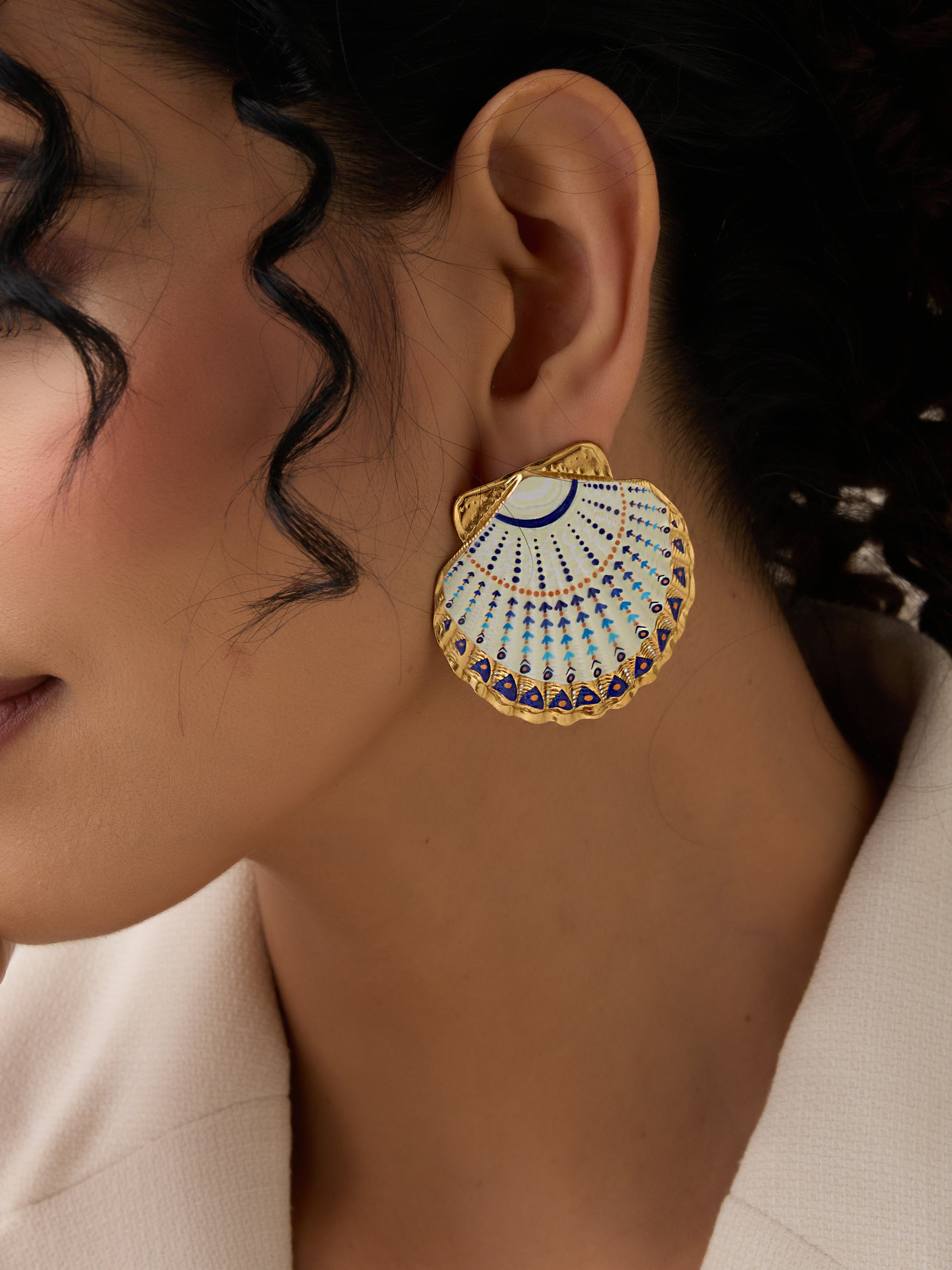 Close-up of a woman wearing a decorative earring with a shell design.