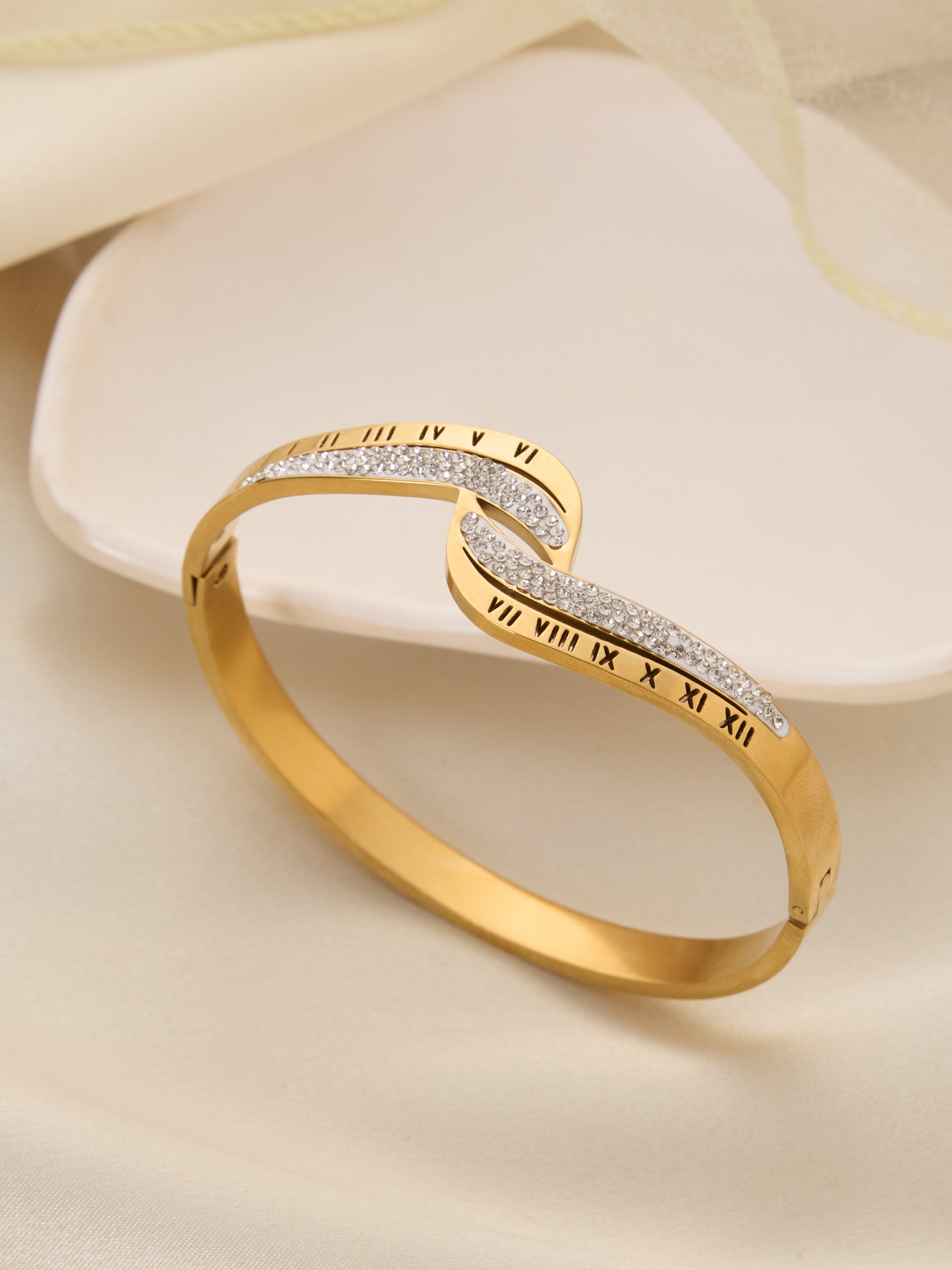 Gold bracelet with Roman numeral design on a soft beige background