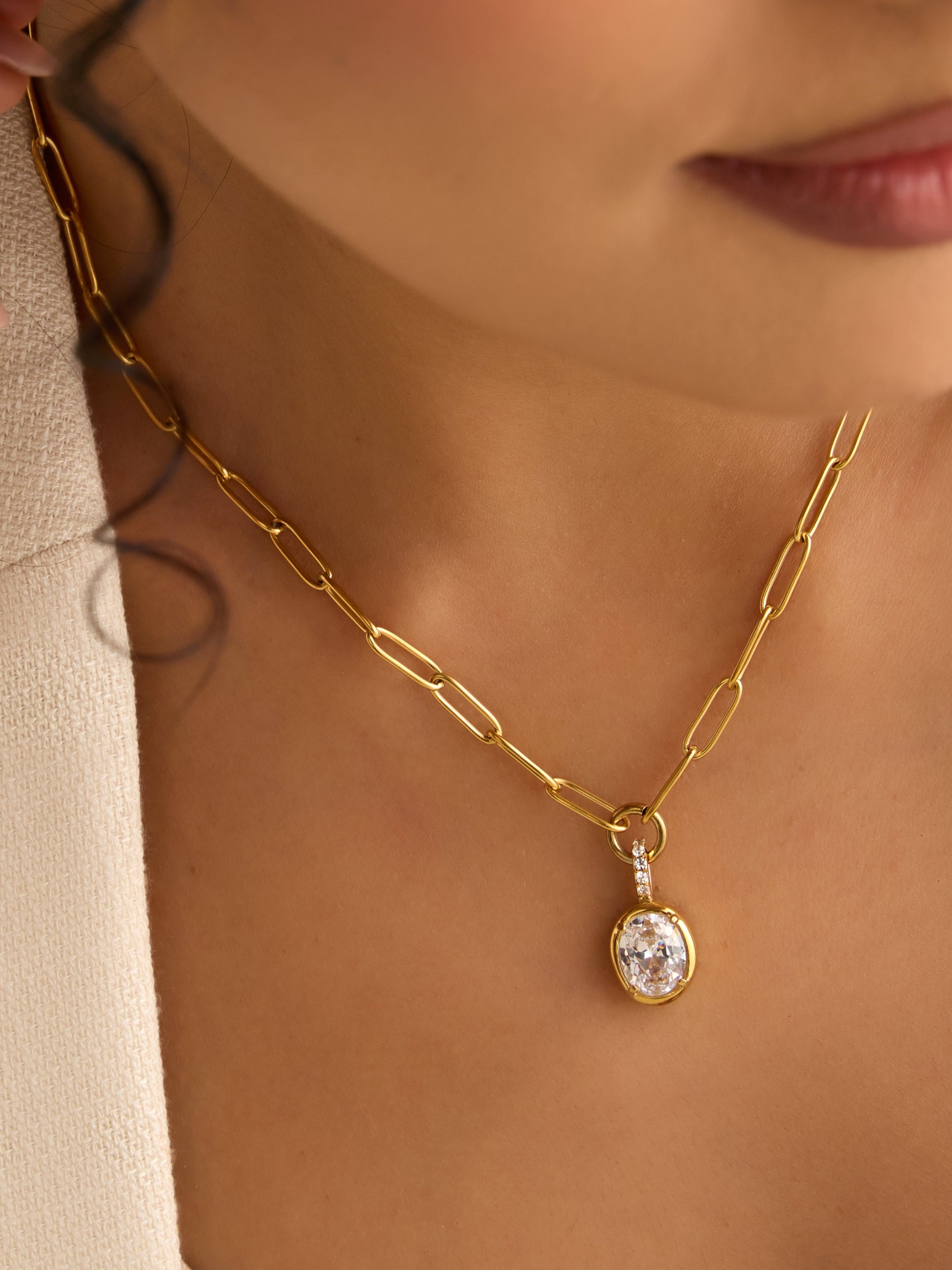 Close-up of a woman wearing a gold necklace with a pendant.