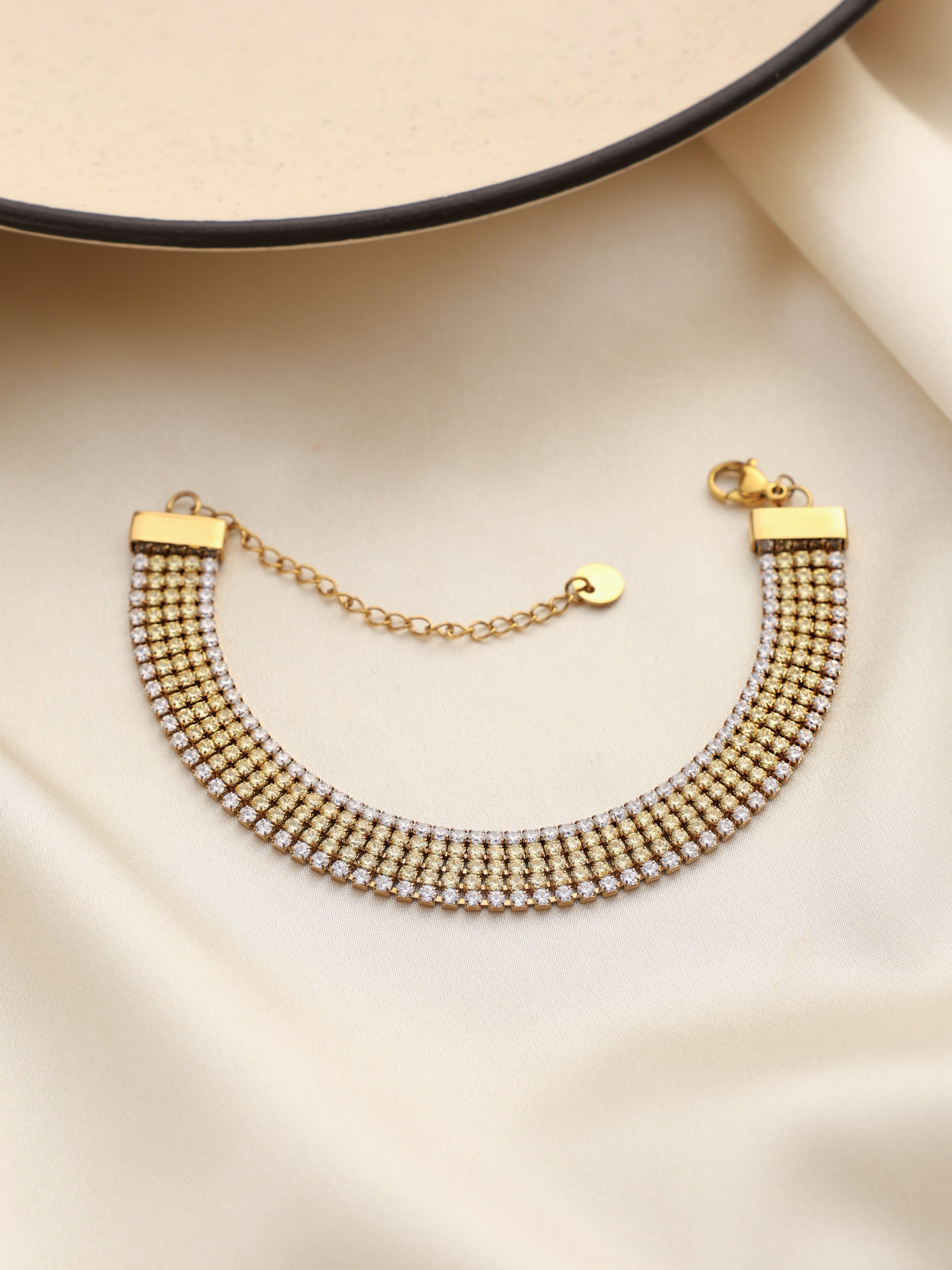 Gold bracelet on a beige satin surface