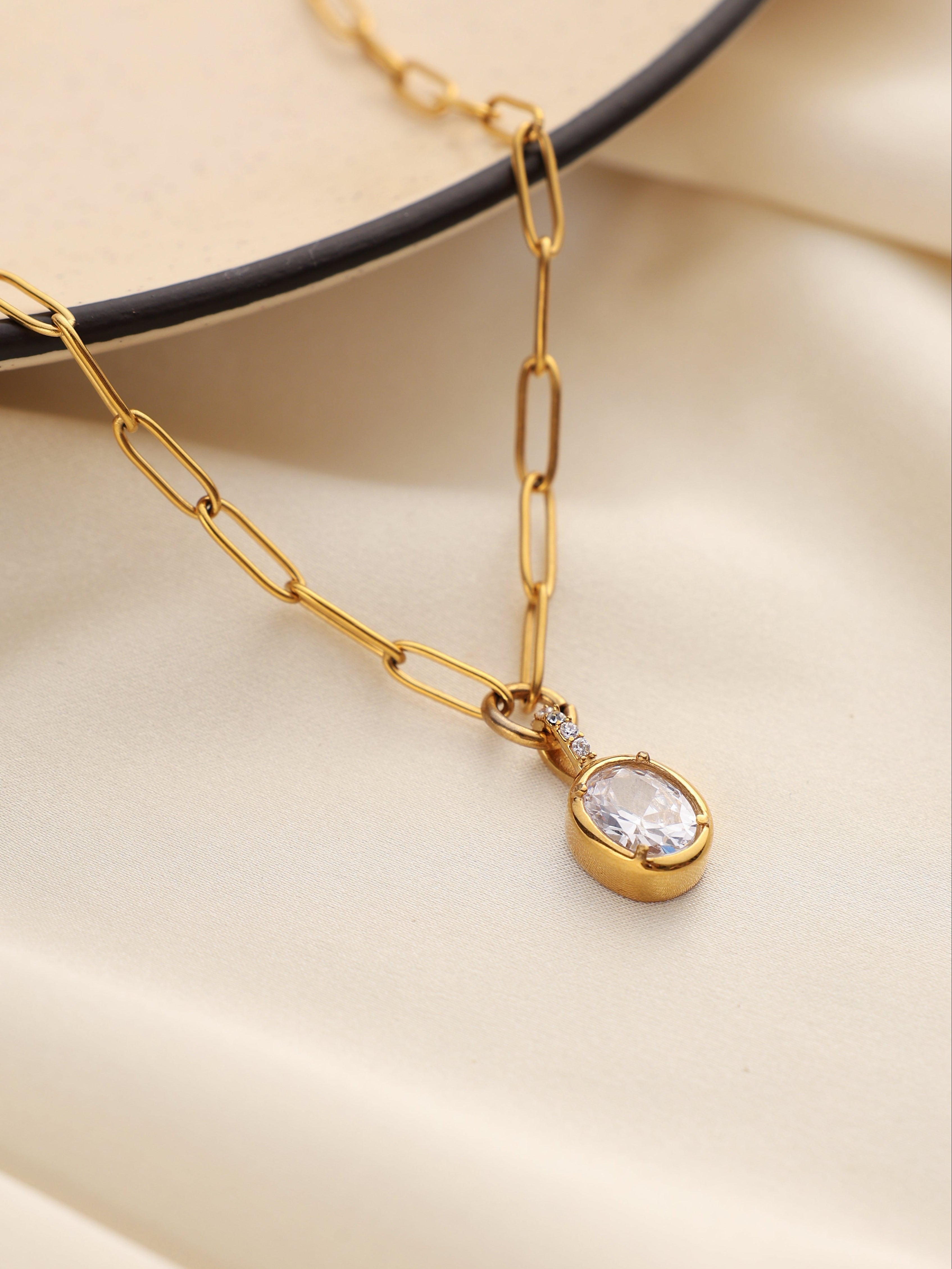 Gold necklace with a diamond pendant on a beige background